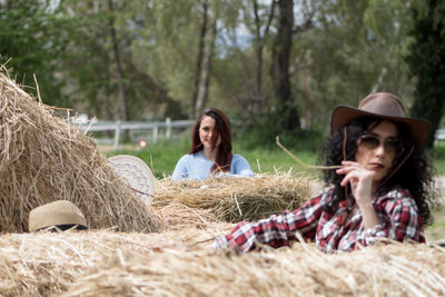 Friends relaxing on field against trees