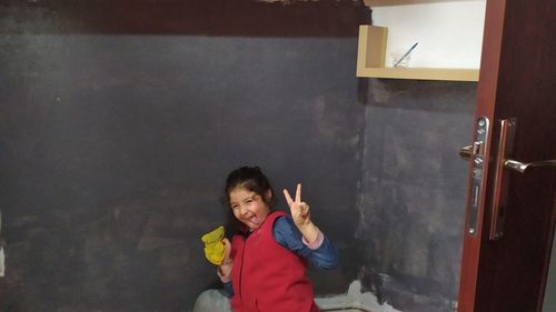 Portrait of a smiling young woman standing against wall