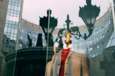 Reflection of statue on glass window in city