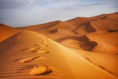 Sand dunes in desert against sky