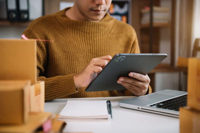 Midsection of man using digital tablet at office