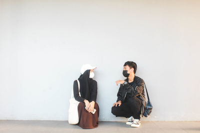 Young couple sitting on floor against wall