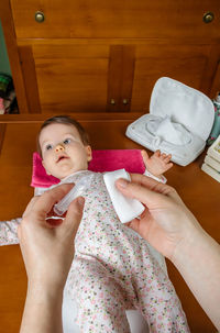 Cropped hand of mother by baby relaxing at home