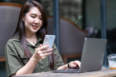 Young woman using digital tablet while sitting on table