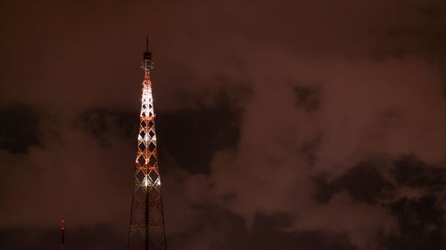 Low angle view of communications tower against cloudy sky