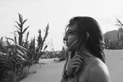 Side view of young woman against sky on field