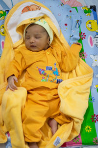 Cute newborn baby sleeping in yellow dress from top angle