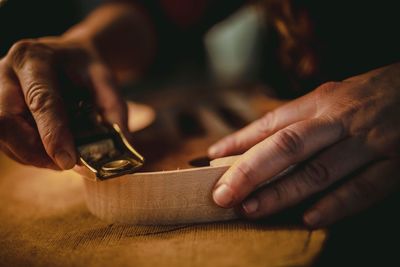 Cropped hand sharpening wood in workshop