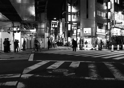 People walking on illuminated street in city