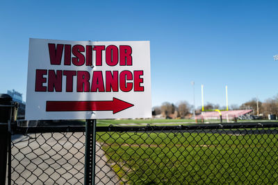 Entrance sign on football stadium fence against clear sky