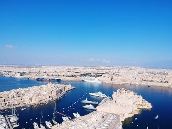 High angle view of harbor by sea against blue sky