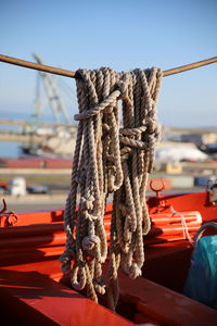 Close-up of rope tied to moored at harbor against sky