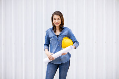 Portrait of smiling woman standing against wall