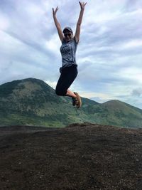 Man jumping on mountain against sky