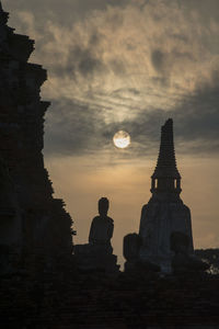 Silhouette of statues under cloudy sky