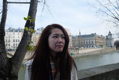 Portrait of beautiful woman in city against sky