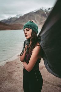 Young woman wearing hat standing against mountain