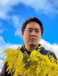 Portrait of man against yellow flowering plants against sky