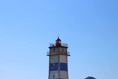 Low angle view of lighthouse by building against clear sky