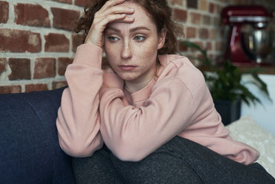 Portrait of young woman sitting on sofa at home