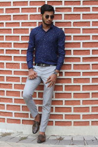 Portrait of young man standing against brick wall