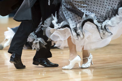 Low section of couple dancing on hardwood floor