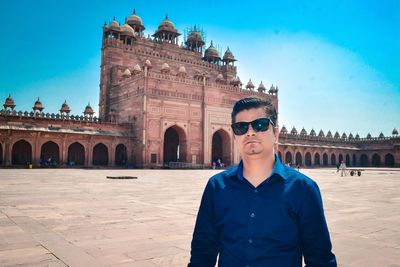 Portrait of man wearing sunglasses standing against fort