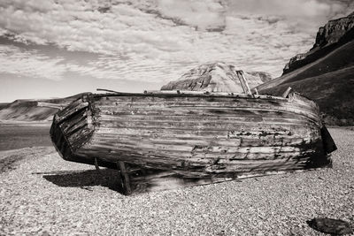 Abandoned boat on beach against sky