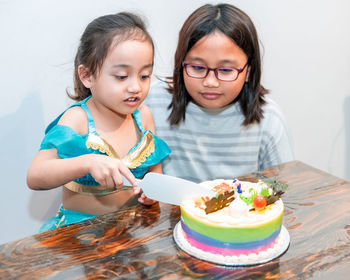 Little girl is cutting her birthday cake. celebrating at home with family during quarantine.