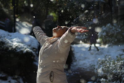 Happy woman with arms raised wearing warm clothing during winter