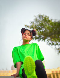 Low angle portrait of young woman against sky