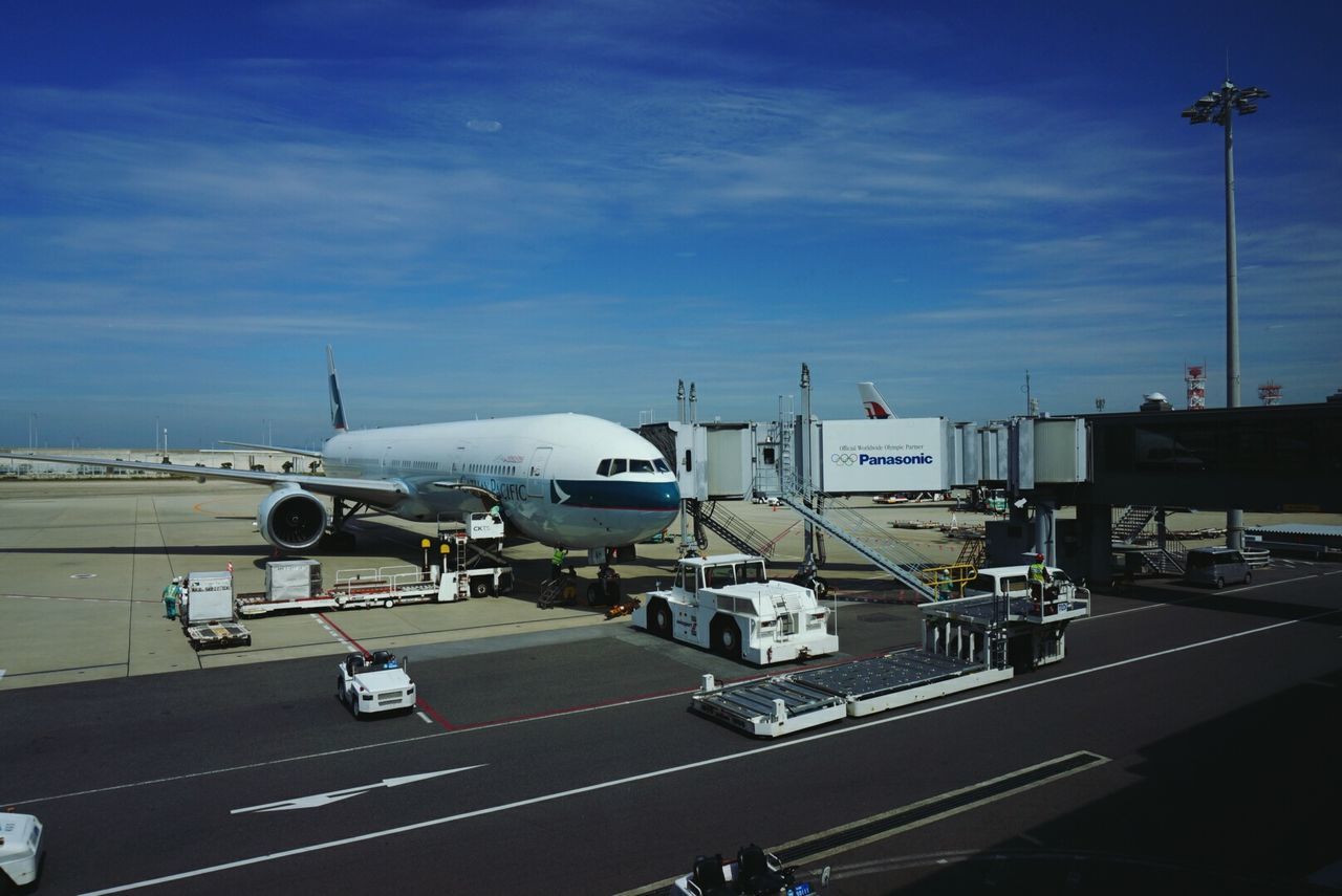 transportation, mode of transport, airplane, sky, public transportation, air vehicle, land vehicle, car, travel, on the move, built structure, cloud - sky, road, architecture, building exterior, city, journey, blue, airport runway, street