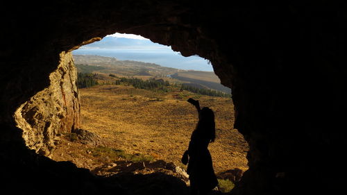 Silhouette of person standing in cave