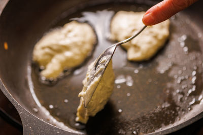 Spoon puts semi-liquid dough into a preheated pan covered with vegetable oil