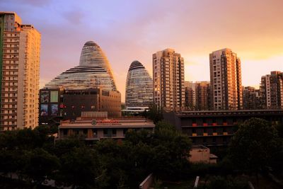 Modern cityscape against sky during sunset