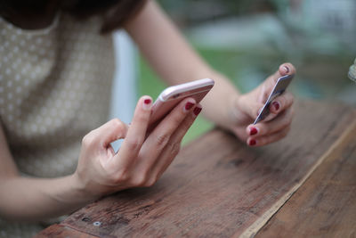 Midsection of woman using phone and credit card on table