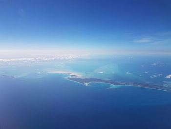 Aerial view of city by sea against blue sky