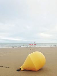 Close-up of yellow umbrella on beach against sky