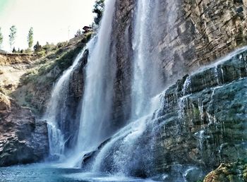 Scenic view of waterfall in forest against sky