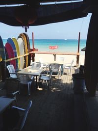 Empty chairs and tables at beach against clear sky