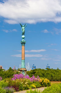 Statue of flowering plant against cloudy sky