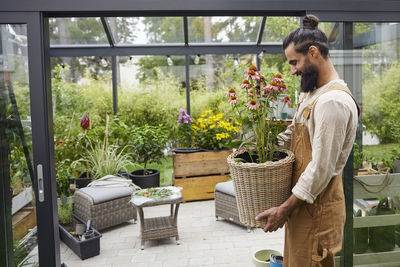 Rear view of woman standing in greenhouse