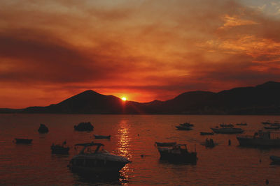 Boats moored in sea against sky during sunset