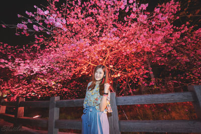 Portrait of woman standing by flowering tree