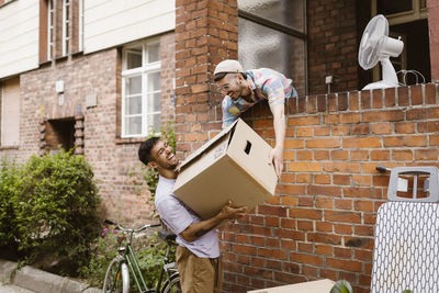 Happy gay couple helping each other during relocation of house