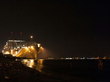 Illuminated sea against clear sky at night