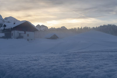 Scenic view of snow covered landscape and houses against sky