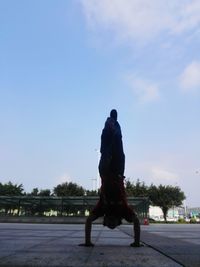 Rear view of man with arms outstretched against sky