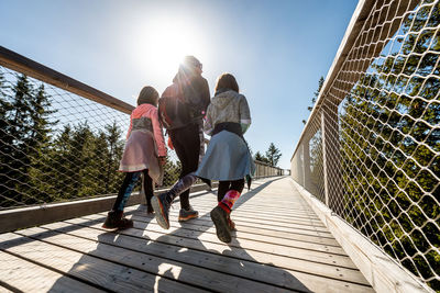 Rear view of people walking on footbridge