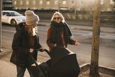 Mothers walking with baby stroller along street